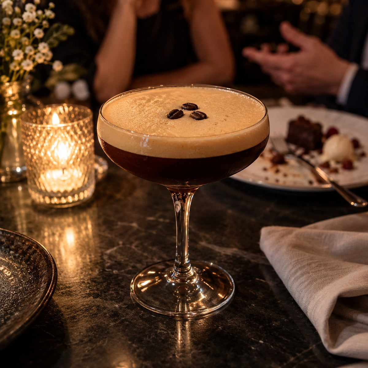 Serveersuggestie: een espresso mocktini met schuimkraag en drie koffiebonen in een coupeglas.